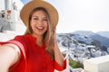 Fashion traveler girl taking selfie photo in Oia picturesque greek village of Santorini Island. Young woman enjoying holidays in Royalty Free Stock Photo