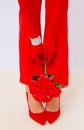 Fashion unrecognizable Lady legs in red pants and shoes. Retro gloves and bracelets. Holding Flowers decor. Minimalist elegant