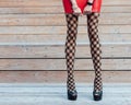 Fashion. A very girl with long legs in fashionable, fishnet stockings, a short red leather skirt and black high-heeled shoes Royalty Free Stock Photo