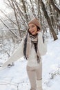 Beautiful woman with dark hair in elegant clothes posing in snow forest