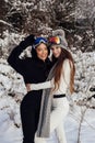 Beautiful women with dark hair in warm sportive clothes posing in snow forest