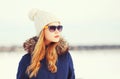 Fashion winter portrait pretty blonde woman wearing a jacket hat and sunglasses looks away over snowy Royalty Free Stock Photo