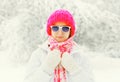 Fashion winter portrait young woman wearing colorful knitted hat, sunglasses over snowy background Royalty Free Stock Photo