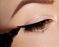 Fashion woman applying eyeliner on eyelid, eyelash. Using makeup brush, shape black line. Professional make-up artist Royalty Free Stock Photo