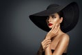 Fashion Woman in Black Wide brim Hat with Red Lips Makeup side view. Elegant Lady Portrait looking away over Gray. Beautiful Model Royalty Free Stock Photo