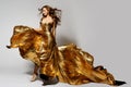 Fashion Woman Dancing in Golden Dress with Waving Hair and Flying Silk Fabric. Model in Glittering Long Evening Gown. Beauty Girl Royalty Free Stock Photo