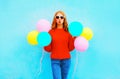 Fashion woman does an air kiss with colorful balloons on blue