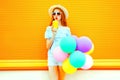 Fashion woman drinks a fruit juice holds an air colorful balloons Royalty Free Stock Photo