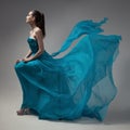 Fashion woman in fluttering blue dress. Gray background. Royalty Free Stock Photo