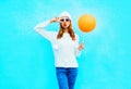 Fashion woman holds orange balloon in white hat on a blue