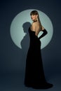 Fashion Woman in long Black Dress with Gloves in Spotlight. Elegant Lady in evening Gown with golden Earrings. Beautiful Girl Dark Royalty Free Stock Photo