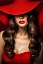 Fashion Woman in Red Dress and Hat with full Red Lips Makeup. Elegant Lady hidden Face. Brunette Sexy Girl with Curly Hair