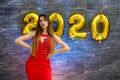 Fashion woman in red dress posing on grey background with golden air balloon 2020