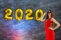 Fashion woman in red dress posing on grey background with golden air balloon 2020