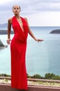 Fashion woman in red dress posing on tropical sea