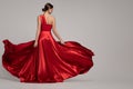 Fashion woman in red long dress on gray background. Back view Royalty Free Stock Photo