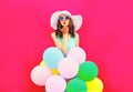 Fashion woman is sends an air kiss holds an air colorful balloons on pink background Royalty Free Stock Photo
