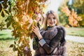 Fashion woman. Smiling girl in fur coat posin in autumn park with trees and ivy Royalty Free Stock Photo