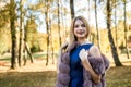 Fashion woman. Smiling girl in fur coat posin in autumn park with trees and ivy Royalty Free Stock Photo