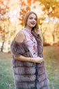 Fashion woman. Smiling girl in fur coat posin in autumn park with trees and ivy Royalty Free Stock Photo