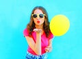 Fashion woman in sunglasses with yellow air balloon sends an air kiss over colorful blue Royalty Free Stock Photo