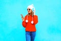 Fashion woman uses smartphone listens to music in wireless headphones in red sweater