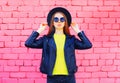 Fashion woman wearing a black hat and yellow knitted sweate rjacket over colorful pink bricks Royalty Free Stock Photo