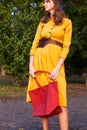 Fashion woman wearing yellow dress and holds red trendy handbag