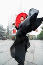 Fashion woman. Young beautiful chinese girl posing outdoor wearing long black dress with high heels holding red umbrella over Royalty Free Stock Photo