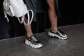 Fashion women clothes. Stylish women`s shoes. Casual design. Close-up of female legs in silver leather sneakers. Street style.