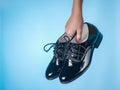Fashion women`s shoes with laces in baby`s hand on blue background. Royalty Free Stock Photo