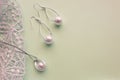 Fashion women`s silver accessories - earrings and pendant with pearls on light background with rich openwork lace, top view, flat