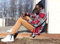 Fashion young african man sitting, using smartphone listens to music Royalty Free Stock Photo