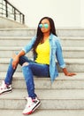 Fashion young african woman wearing a sunglasses and jeans shirt sitting on stairs in city Royalty Free Stock Photo