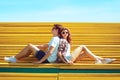 Fashion young couple teenagers resting in the city park sitting on the bench Royalty Free Stock Photo