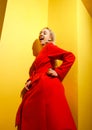 Fashion young girl blogger dressed in stylish red coat poses with the gold little duck figurine in her hands on the