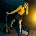 Fashion young hipster woman with curly hair with red guitar in neon lights. Rock musician is playing electrical guitar Royalty Free Stock Photo