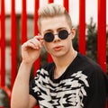 Fashion young man with hairstyle wears stylish round sunglasses Royalty Free Stock Photo