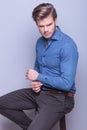 Fashion young man sitting , fixing his sleeve Royalty Free Stock Photo