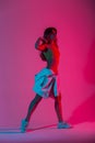 Fashion young woman dancer in a trendy youth clothes in stylish sneakers dancing in the studio with bright pink neon color in Royalty Free Stock Photo