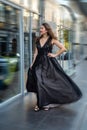 Fashion young woman full length in evening black dress walking in city daytime Royalty Free Stock Photo