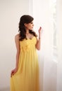 Fashion young woman in long yellow dress looking out the window Royalty Free Stock Photo
