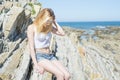 Fashion young woman sitting on sea rocks. Royalty Free Stock Photo