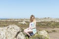 Fashion young woman sitting on sea rocks. Royalty Free Stock Photo