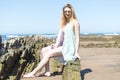 Fashion young woman sitting on sea rocks. Royalty Free Stock Photo