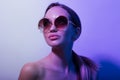 Fashiona girl with round glasses posing in a neon light in the studio. Portrait Royalty Free Stock Photo