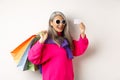 Fashionable asian old lady going shopping, holding paper bags and plastic credit card, wearing stylish sunglasses Royalty Free Stock Photo