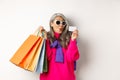 Fashionable asian old lady going shopping, holding paper bags and plastic credit card, wearing stylish sunglasses Royalty Free Stock Photo