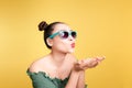 Fashionable asian woman in trendy sunglasses sends a kiss against bright yellow background Royalty Free Stock Photo