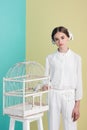 fashionable attractive girl in white outfit with parrot in cage on turquoise Royalty Free Stock Photo